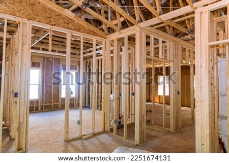 New residential construction project is framing an unfinished wood frame house with basic electrical wiring as part construction process Royalty-Free Stock Photo #2251674131