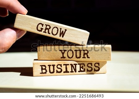 Closeup on businessman holding a wooden blocks with text 'GROW YOUR BUSINESS', business concept