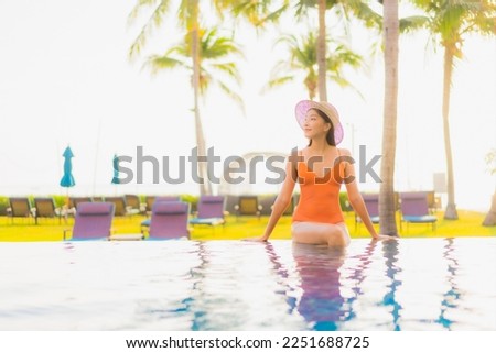 Portrait beautiful young asian woman relax smile leisure around outdoor swimming pool nearly sea beach ocean at sunset time for vacation