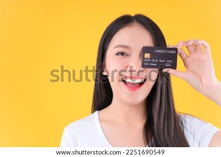 Photo happy positive pretty asian woman smile showing, presenting credit card for payment or paying online business payment credit card for confident money and financial concepts yellow background.