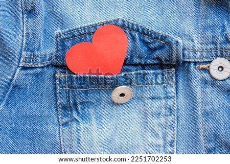 Close up of a red heart showing from a denim jacket pocket. A concept of love, friendship, St. Valentine celebration. Royalty-Free Stock Photo #2251702253