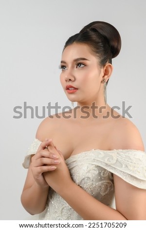 Portrait of beautiful Asian bride in white wedding dress in cheerful pose with charming smile on white background, empty space for insert your advertisement