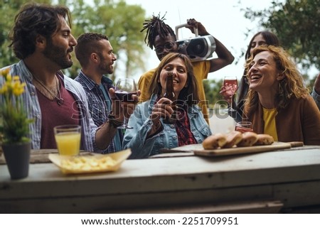A diverse group of friends bond over drinks at sunset in an outdoor bar setting, representing diversity, togetherness and the culture of mixology. The picture captures the essence of summer