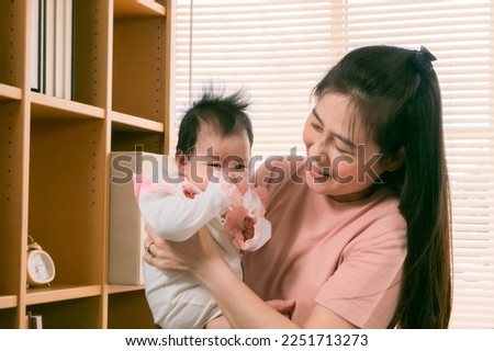 Asian beautiful mother holding adorable newborn baby with love and care, Happy affectionate mother spending time with adorable infant,  motherhood lifestyle taking care taddler at home.