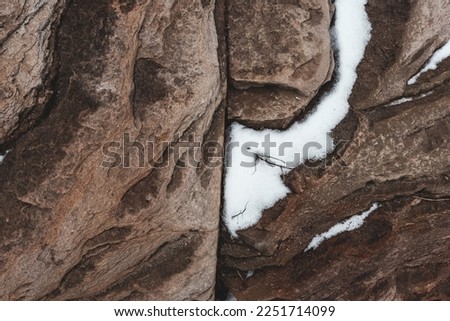 Texture of stone granite rock with snow. The background is natural.
