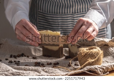 Woman is wrapping a beautiful natural coffee soap in craft paper. Concept of handmade gifts, hobbies, eco friendly behavior.