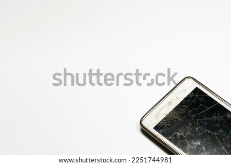 Photo of a smartphone with a broken damaged display. Modern smartphone with a damaged glass screen on a white background. The device needs repair.