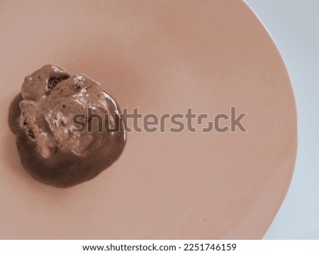 Chocolate ice cream is melting on the plate.