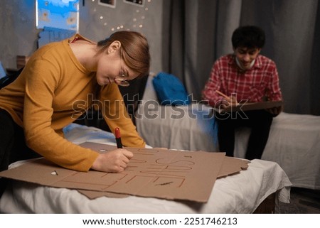 Students in a dorm room painting posters to protest to save the planet. Copy space