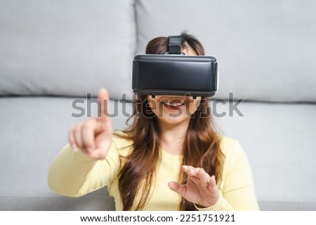 Young Asian woman gamer wearing virtual reality touching air during the VR experience  Future home technology player hobby playful enjoyment concept