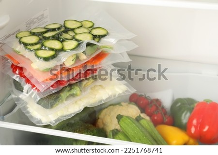 Vacuum bags with different vegetables in fridge, space for text. Food storage Royalty-Free Stock Photo #2251768741
