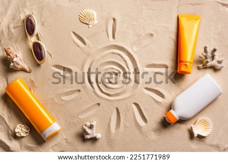Sunblock lotion tubes and sunglasses on sandy beach background. Summer vacation and skin care concept, sunscreen products, spf uv-protect cosmetics. Royalty-Free Stock Photo #2251771989