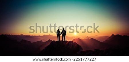 Silhouette Couple of man and woman reaching summit enjoying freedom and looking towards mountains sunset. Alps, Allgaeu, Bavaria, Germany. Royalty-Free Stock Photo #2251777227