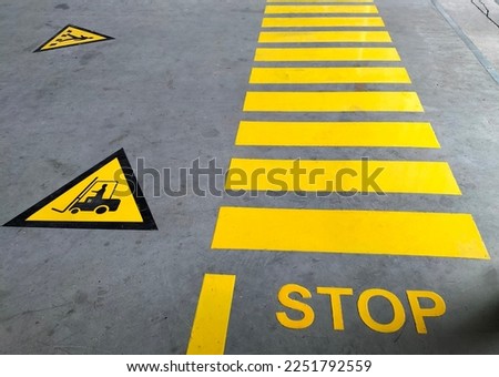 Walkway signs and painted yellow on the factory floor. scratched cement surface industrial safety sign