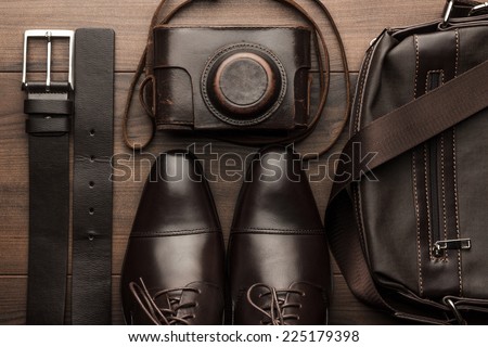 brown shoes, belt, bag and film camera on the wooden table Royalty-Free Stock Photo #225179398