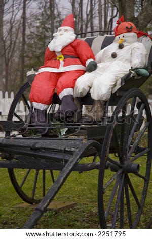 Santa and snowman sitting in an antique wood horse drawn wagon