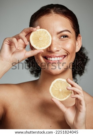 Face, skincare and woman with lemon in studio isolated on a gray background. Fruit, organic cosmetics and happy female model holding lemons for healthy diet, vitamin c or minerals, wellness or beauty