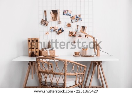 Workplace with Christmas gift, cup and folders near light wall