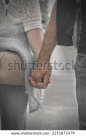 Two hands together, slightly desaturated, with vignetting . The woman is Caucasian. The man has a different skin colour. 