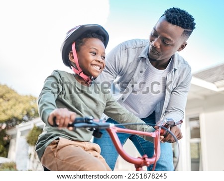 Look at him go. Shot of a father teaching his son to ride a bicycle outdoors. Royalty-Free Stock Photo #2251878245