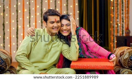 Young Indians siblings showing love and care - brother-sister relationship - Raksha Bandhan concept, Indian Model . Good looking adults in traditional wear. Cute brother teasing and giving gift to ... Royalty-Free Stock Photo #2251889989