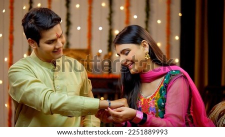 Indian sister tying rakhi on her brother's wrist and expressing the love - Raksha Bandhan, Indian Model. Loving sister ties a sacred thread embellished with her love and affection towards the broth... Royalty-Free Stock Photo #2251889993