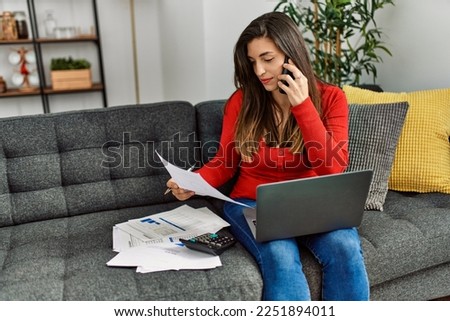 Young woman talking on the smartphone working at home