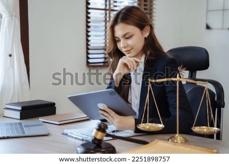 Lawyer female in office looking at tablet with thinking reading email on tablet and laptop.