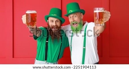 Happy bearded men drinking beer on red background. St. Patrick's Day celebration