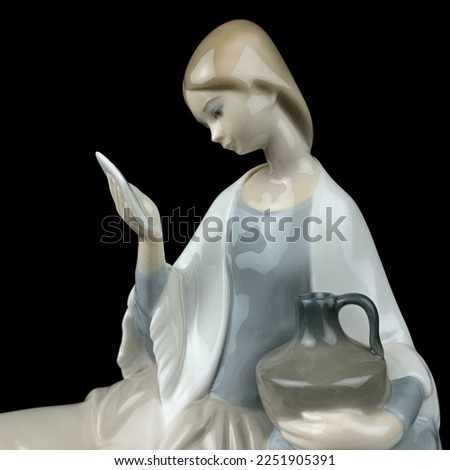 Statue of Virgin Mary isolated on black background, clipping path included. vintage figurine of a woman reading a book