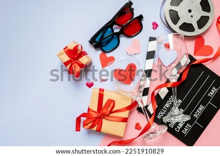 beautiful composition with hearts, movie clapperboard, valentines day style gifts on blue and pink background. movie night concept. love date for two. copy space. flat lay. top view.