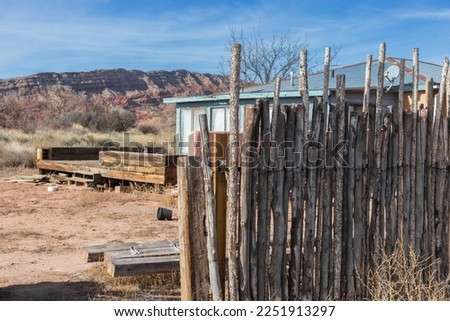 Abandoned house behind a wooden pole fence with desert mountains in the background