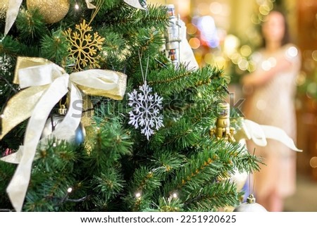 Christmas tree background and Christmas decor. Silver,gold,transparent shiny ball and decorations on green fir. silhouette of a young woman blurred.