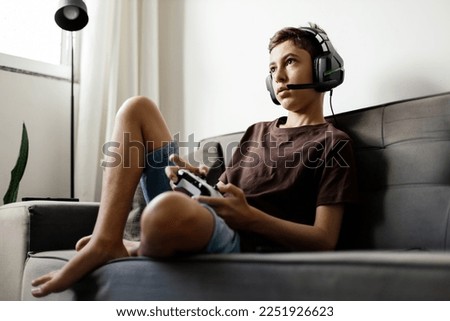 Teenager playing video games at home Royalty-Free Stock Photo #2251926623
