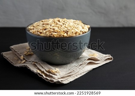 Wholegrain Oat Flakes in a Bowl on a black background, side view.  Royalty-Free Stock Photo #2251928569