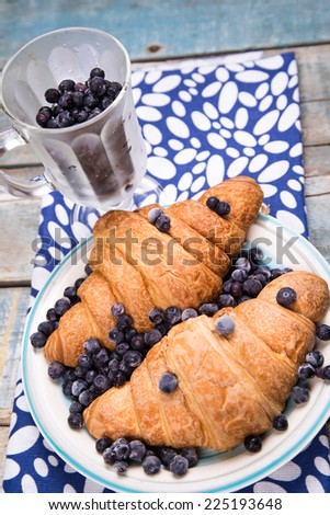 fresh croissant with frozen blackberry in transparent cup in studio