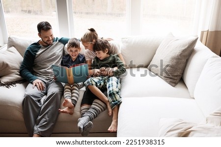 Happy, learning and parents reading a book with children for bonding, fun and quality time. Knowledge, information and boys excited about a story on the lounge sofa with their mother and father Royalty-Free Stock Photo #2251938315