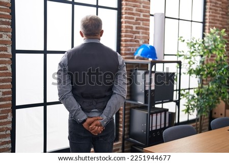 Middle age grey-haired man architect standing on back view at office