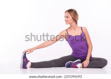 Sportswoman does the exercises sitting with  straight and banded  legs and holding toes with hands  isolated on white background with copy place