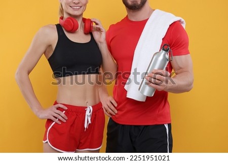 Athletic people with headphones, thermo bottle and towel on yellow background, closeup