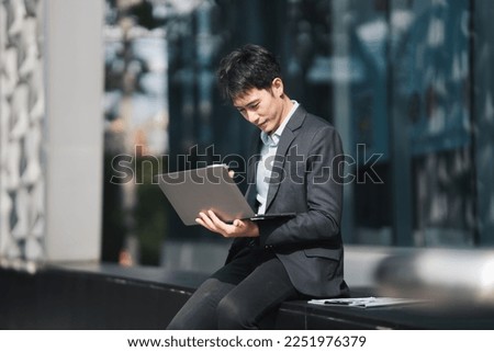 Handsome young manager working on laptop while sitting outdoors on the stairs, concept of work life balance.