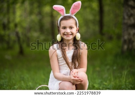 girl with rabbit ears and easter eggs on her ears walking in the park, happy easter. High quality photo
