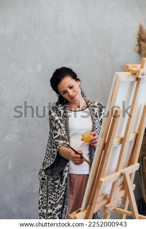 a woman artist paints a picture on an easel standing at an easel