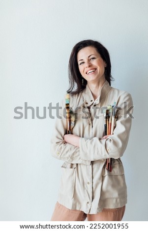 a woman artist with brushes for drawing stands on a white background