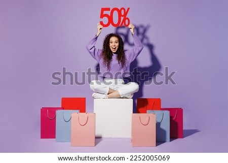 Full body young woman wear pullover sit at shopping paper package bag after hold overhead 50 % percent discount sign isolated on plain pastel light purple background Black Friday sale buy day concept