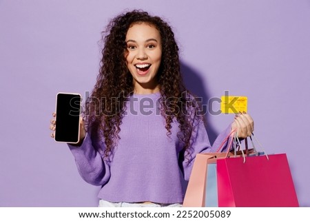 Young happy woman wear pullover hold paper package bags after shopping use blank screen mobile cell phone credit bank card isolated on plain pastel purple background Black Friday sale buy day concept Royalty-Free Stock Photo #2252005089
