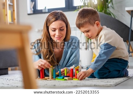 Mother and her son playing on the floor with colorful didactic toys at home. Early education and development  Royalty-Free Stock Photo #2252013355