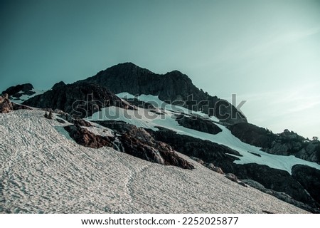Blue skies over a rocky and snow contrasted mountain 