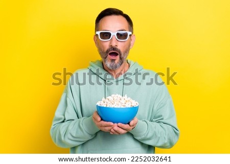 Photo of retired excited man brunet hair open mouth speechless hold popcorn stunned incredible moment film isolated on yellow color background