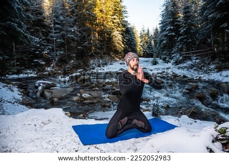 Motivation yoga and meditation on the wild nature near the river on the snow